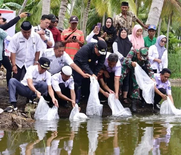 Penjabat (Pj) Gubernur Sulsel, Bahtiar Baharuddin (baju dan topi hitam) saat menebarkan bibit ikan di Bone, Rabu (13/3).