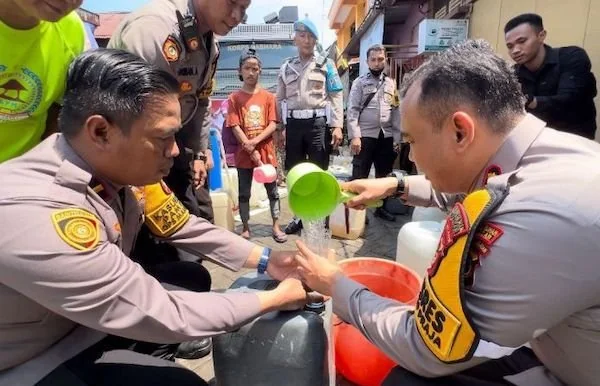 Kapolres Pelabuhan Makassar, AKBP Restu Wijayanto (kanan) bersama anggota Polres Pelabuhan Makassar saat menyalurkan air bersih (Dok: Ist)