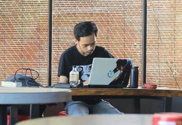 Salah seorang pengunjung kafe di Makassar mengerjakan tugas (Dok: Nofi KabarMakassar).