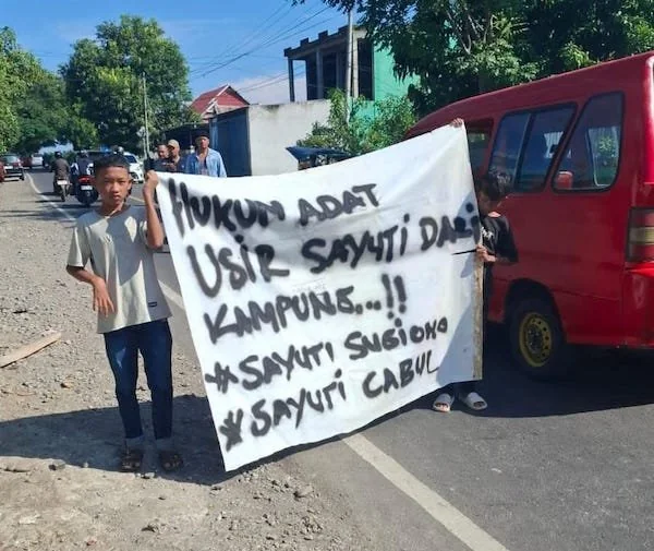 Tuntutan warga saat membentangkan spanduk ditengah jalan. (Foto/ist).