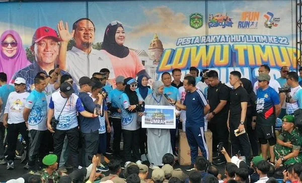 Gubernur Sulawesi Selatan, Andi Sudirman Sulaiman, menyerahkan hadiah umrah kepada Nurlina, bidan PNS dari UPTD Puskesmas Berau pada acara Fun Run Luwu Timur 2025 dan Gerakan Anti Mager Sulsel (Dok: Ist)