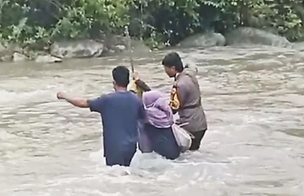 Aksi heroik bhabinkamtibmas saat membantu warga menyebrang (Dok : Ist).