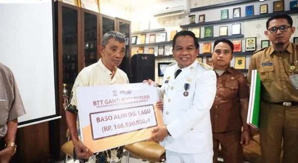 Pj. Bupati Jeneponto Junaedi saat menyerahkan uang ganti rugi kepada Baso Alim Lagu (Dok : ist).