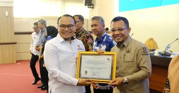 Anggota Ombudsman RI, Robert Na Endi Jaweng saat menyerahkan penghargaan kepada Kadisdukcapil Jeneponto, Mustaufiq di Ruang Pola Kantor Gubernur Sulawesi Selatan. (Ist).
