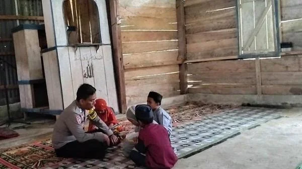 Bripka Nur Alam saat mengajarkan kitab Al Qur'an kepada anak anak di pedalaman Kabupaten Mamasa (Dok: Ist)