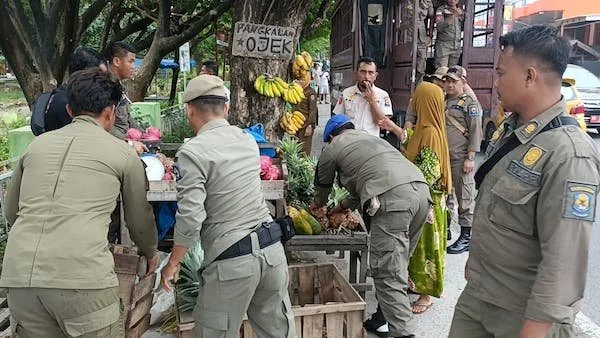 Petugas Satpol PP saat menertibkan sejumlah lapak pedagang di depan areal Taman Makam Pahlawan (TMP) dan sepanjang jalan depan Pasar Tradisional Karisa. (foto/ist).