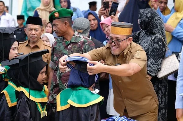 Bupati H. Paris Yasir saat menaikkan tali toga salah santri di di acara Wisuda LPPTKA BKPRMI Jeneponto. (Ist).