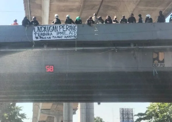 Sekelompok orang membentangkan spanduk bertuliskan “Undangan Perang Terbuka” untuk IPMIL di Flyover Makassar. Dok. Ist